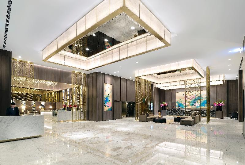 臺北 板桥凯撒大饭店酒店 外观 照片 The image shows a modern and elegantly designed hotel lobby. The space features high ceilings with decorative light fixtures hanging from above, providing a bright and welcoming atmosphere. The reception area is seen on the left, with a sleek marble 