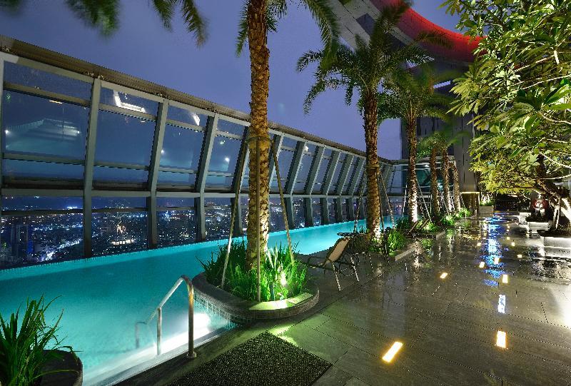 臺北 板桥凯撒大饭店酒店 外观 照片 The photo shows a luxurious rooftop pool area, illuminated at night. There are tall palm trees lining the space, creating a tropical ambiance. The pool itself has a modern design, featuring an infinity edge that blends seamlessly with the city skylin