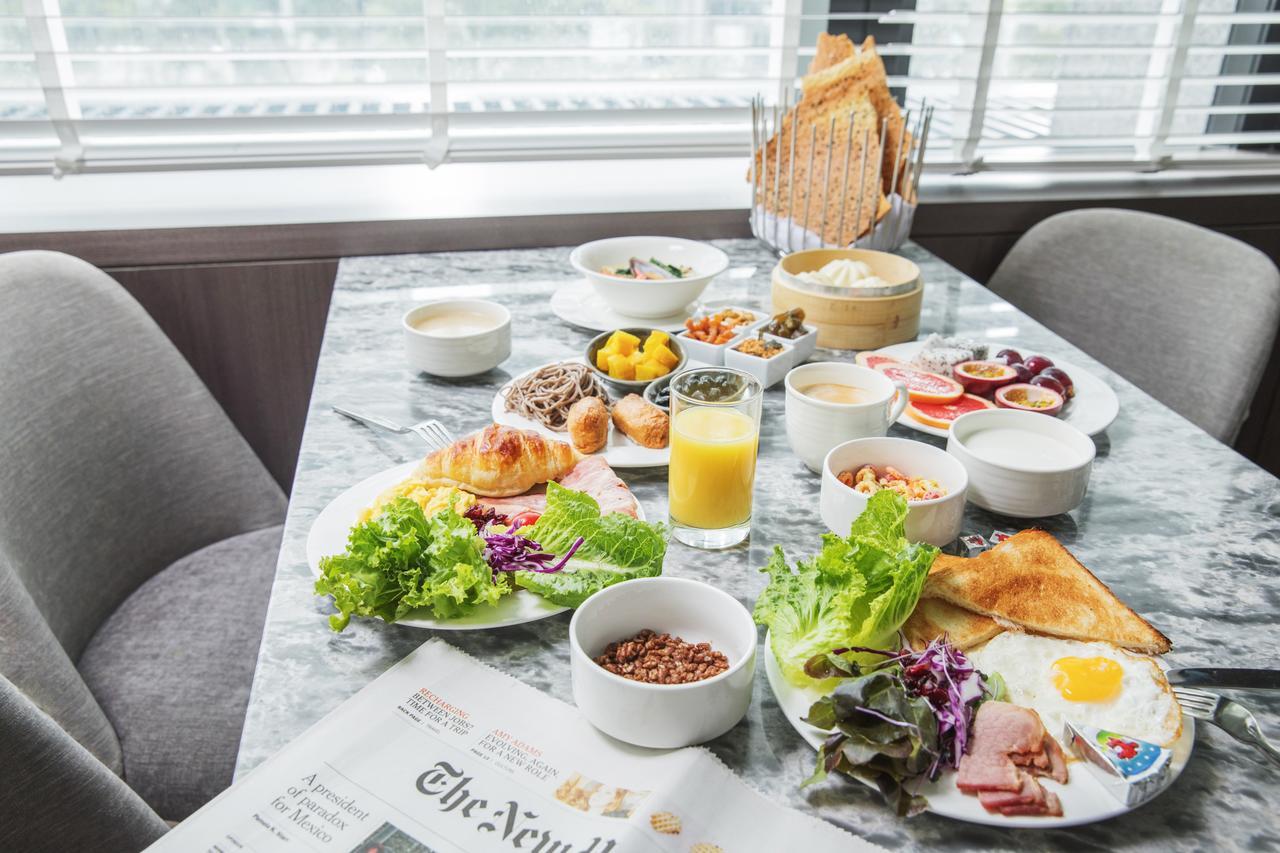 臺北 板桥凯撒大饭店酒店 外观 照片 The photo shows a breakfast spread on a table. There are various plates and bowls filled with food, including fresh vegetables, croissants, toast, and a selection of small dishes, likely containing sides like fruits, yogurt, and possibly meats. There